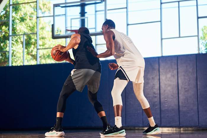 De'Aaron Fox and Stephen Curry work out in a basketball gym.